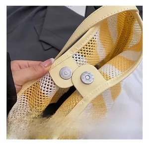 Detail of magnetic silver buckle on yellow and white striped woven bucket bag