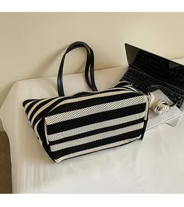 Detail showing high-capacity black and white striped knitted tote with faux leather handles