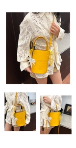 Bright yellow bucket bag with daisy charm and litchi texture on a model