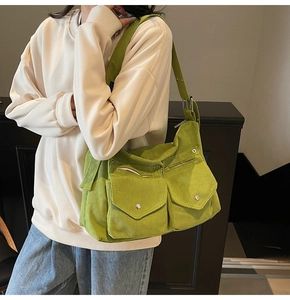 Détail d'un sac en velours côtelé vert avec deux grandes poches avant et bandoulière