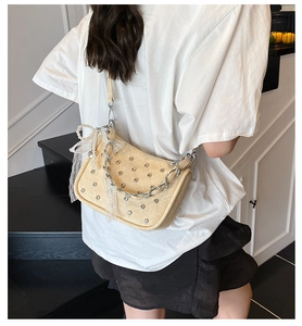 Détail du sac beige tissé avec strass brillants et ruban à nœud en perles