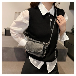 Detail of vintage black denim crossbody bag with silver chain strap and multiple pockets