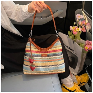 Détail d'un sac hobo tissé arc-en-ciel avec bandoulière en cuir et pendentifs fraises