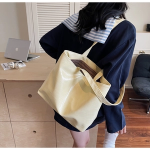 Detailed view of yellow crocodile textured leather tote bag with embossed pattern