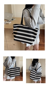 Detail of woven fabric texture and black leather handles on a striped tote bag