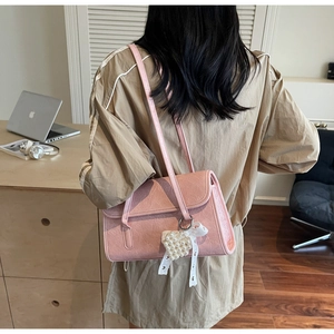 Detail of pink shoulder bag featuring marble texture leather and pearl heart pendant