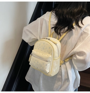 Gros plan d'un mini sac à dos jaune avec détails en strass brillants sur cuir texturé