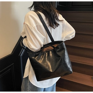 Macro view of black crocodile pattern tote bag with polished finish and dual strap details