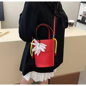 Detail of red leather bucket bag with white flower charm and yellow drawstring