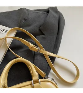 Detail of adjustable long shoulder strap and metal buckle on yellow faux leather bag