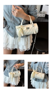 Détail du sac cylindrique matelassé blanc avec grand nœud en dentelle et chaîne