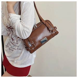 Macro shot of brown glossy leather Boston bag showing dual zippers and metal buckle details