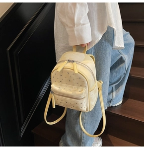 Detail of a beige quilted mini backpack with rhinestone studs shown in a lifestyle setting
