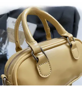 Close-up of pale yellow Boston bag showing smooth leather texture and silver hardware