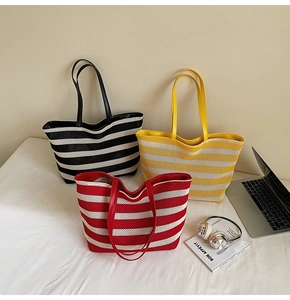 Detailed shot of striped woven tote bags in black, yellow, and red with slim leather straps