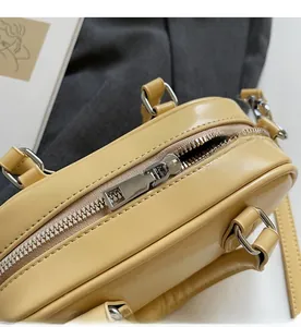 Detailed macro view of the smooth silver metal zipper on a glossy yellow leather handbag
