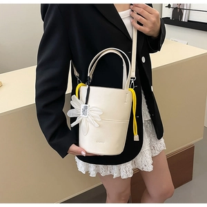 Detail of cream bucket bag with white chiffon flower charm and adjustable shoulder strap