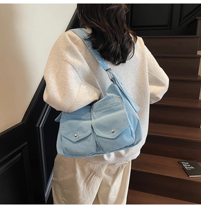 Détail du sac fourre-tout en velours côtelé bleu clair avec poches avant à boutons métalliques