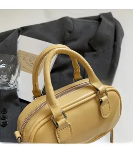 Detailed view of yellow faux leather Boston bag with sturdy handles and metal zippers