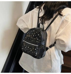 Détail d'un mini sac à dos noir en similicuir avec strass porté par un mannequin femme