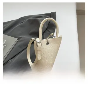 Vue détaillée du sac triangulaire crème avec texture en cuir grainé et boucle métallique