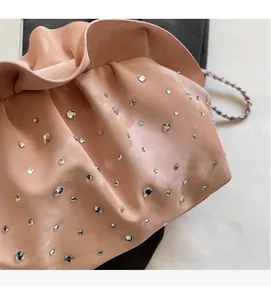 Detail of pink pleated cloud bag with sparkling rhinestones and metal chain strap