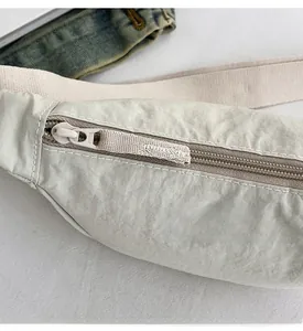 Detail of beige nylon crossbody bag showing smooth hardware zipper and fabric strap