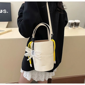 Detail of cream bucket bag with yellow drawstring and large 3D flower charm accessory