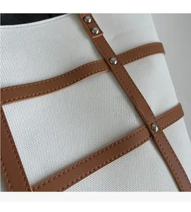 Detailed close-up of textured canvas fabric with brown leather straps and silver metal studs