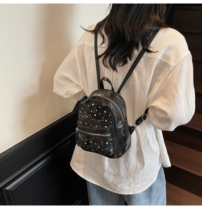 Fashionable mini black backpack with silver studs shown on model in stair setting