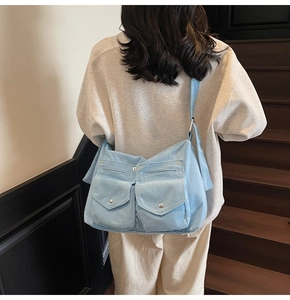 Détail du sac bandoulière en velours côtelé bleu clair avec deux poches et boutons argentés