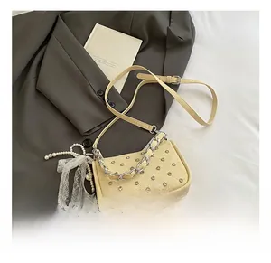 Détail du sac à bandoulière tissé beige avec clous argentés et chaîne en métal