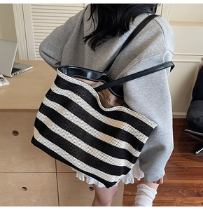 Close-up of black and white striped woven tote bag featuring durable black leather straps