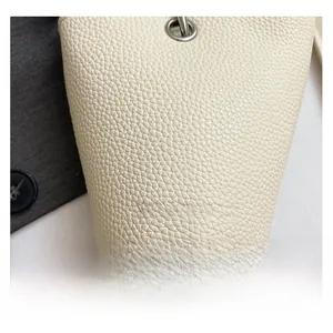 Détail du sac à main en cuir grainé crème avec texte argenté et détails d'oeillets métalliques