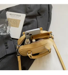 Detail view of yellow crossbody bag interior showing storage capacity for phone and lipstick