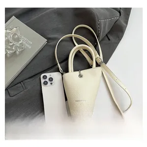 Gros plan du sac seau crème avec texture litchi et bandoulière amovible