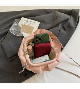 Interior storage capacity of pink pleated cloud bag showing phone and cosmetics