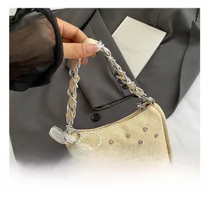 Détail du sac tissé crème avec strass, bandoulière en chaîne et pendentif nœud de perles