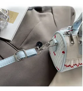 Detail of silver hardware and light blue leather strap on a bow Boston bag