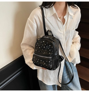 Mini black quilted backpack with silver rhinestones on a model in a casual indoor setting