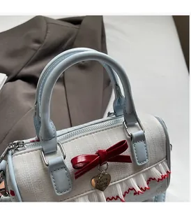 Detail view of pink bow, heart charm and textured fabric on Boston handbag