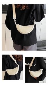 Detail of cream nylon dumpling bag featuring wide adjustable strap and zipper closure