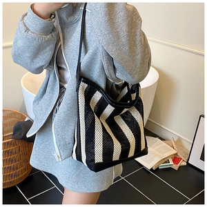 Detalle del bolso tote de malla a rayas blancas y negras con asa de cuero y textura tejida