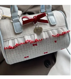 Close-up of heart charm and red leather bow detail on a floral Boston handbag