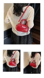 Detail of red leather Boston bag with metallic logo and detachable shoulder strap