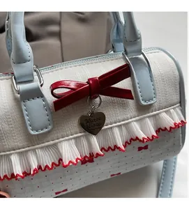 Close-up of bow print handbag featuring red wavy ruffles and heart-shaped metal pendant