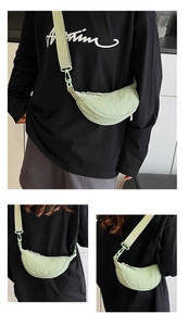 Detail of light green crescent nylon bag with wide strap and ruched texture finish