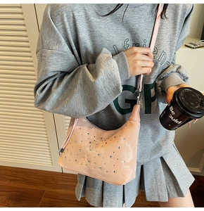 Close-up of pink crescent bag with silver rhinestone embellishments and smooth leather