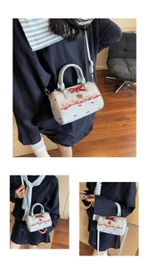 Detail of Boston bag showing red silk bow, gold heart charm, and blue shoulder strap