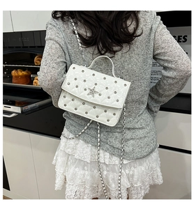 Petit sac à bandoulière blanc matelassé avec étoiles porté par un mannequin en cuisine